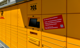 Eine gelbe Poststation der Deutschen Post mit Fächern für Pakete und Briefe